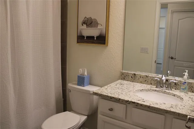a bathroom with a granite countertop toilet sink and mirror
