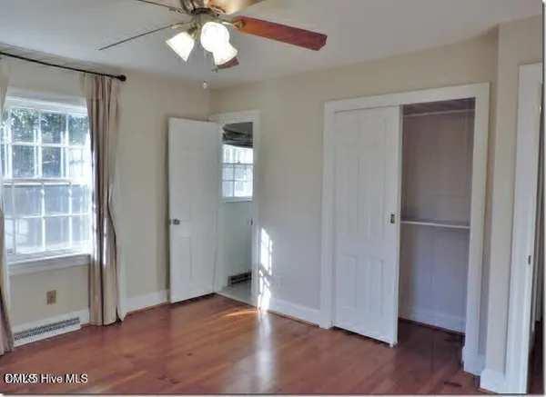 an empty room with wooden floor cabinet and windows
