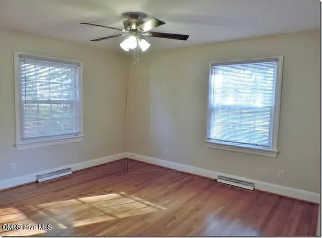 a view of an empty room with wooden floor and a window