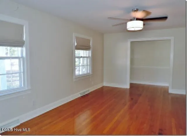 an empty room with wooden floor and windows