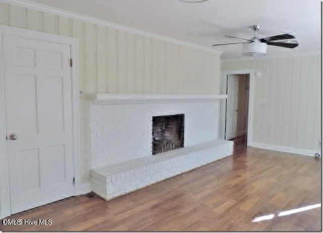 a view of an empty room with wooden floor and a fireplace