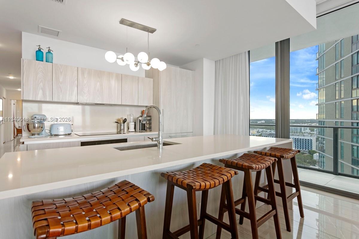 480 Northeast 31st Street, Unit 2307 Miami, FL 33137 - Photo 6 of 47 a kitchen with stainless steel appliances granite countertop a stove top oven a sink with dining table and chairs