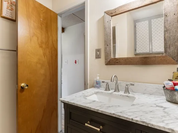 a bathroom with a granite countertop sink and a mirror