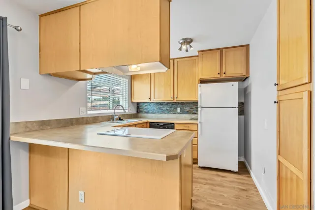 a kitchen with refrigerator a sink dishwasher and cabinets with wooden floor