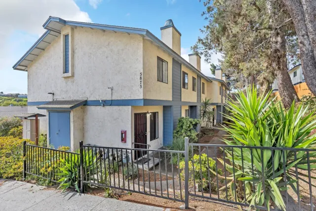 a front view of a house with glass windows and plants
