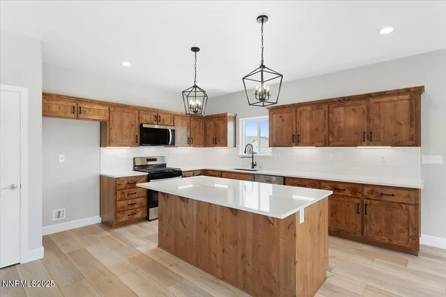 a kitchen with stainless steel appliances granite countertop a sink a stove and a wooden floors