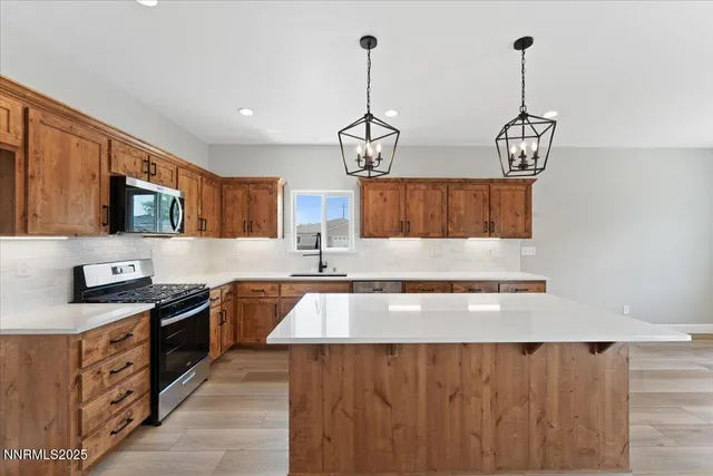 a kitchen with stainless steel appliances granite countertop a sink a stove and a wooden floors