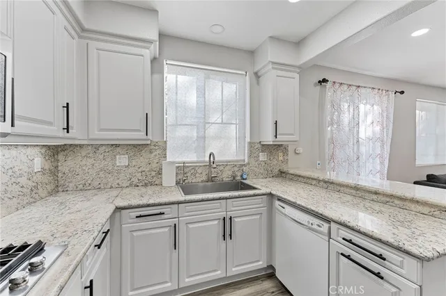 a kitchen with granite countertop white cabinets and white appliances