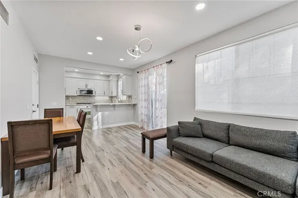 a living room with stainless steel appliances kitchen island granite countertop furniture and a wooden floor
