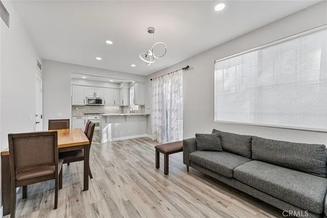 a living room with stainless steel appliances kitchen island granite countertop furniture and a wooden floor