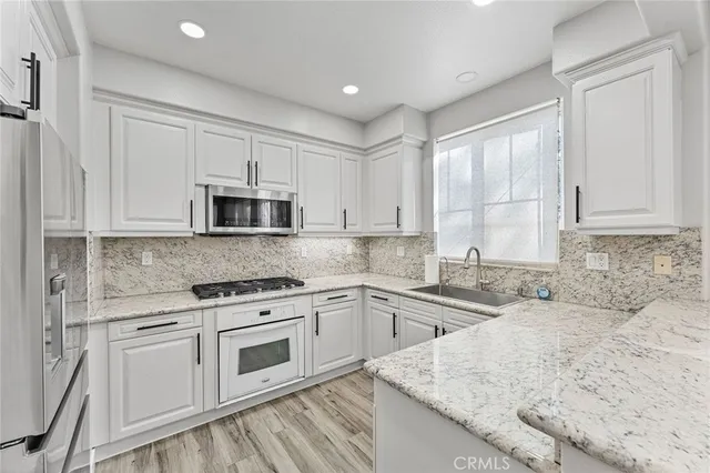 a kitchen with granite countertop a sink a stove and cabinets