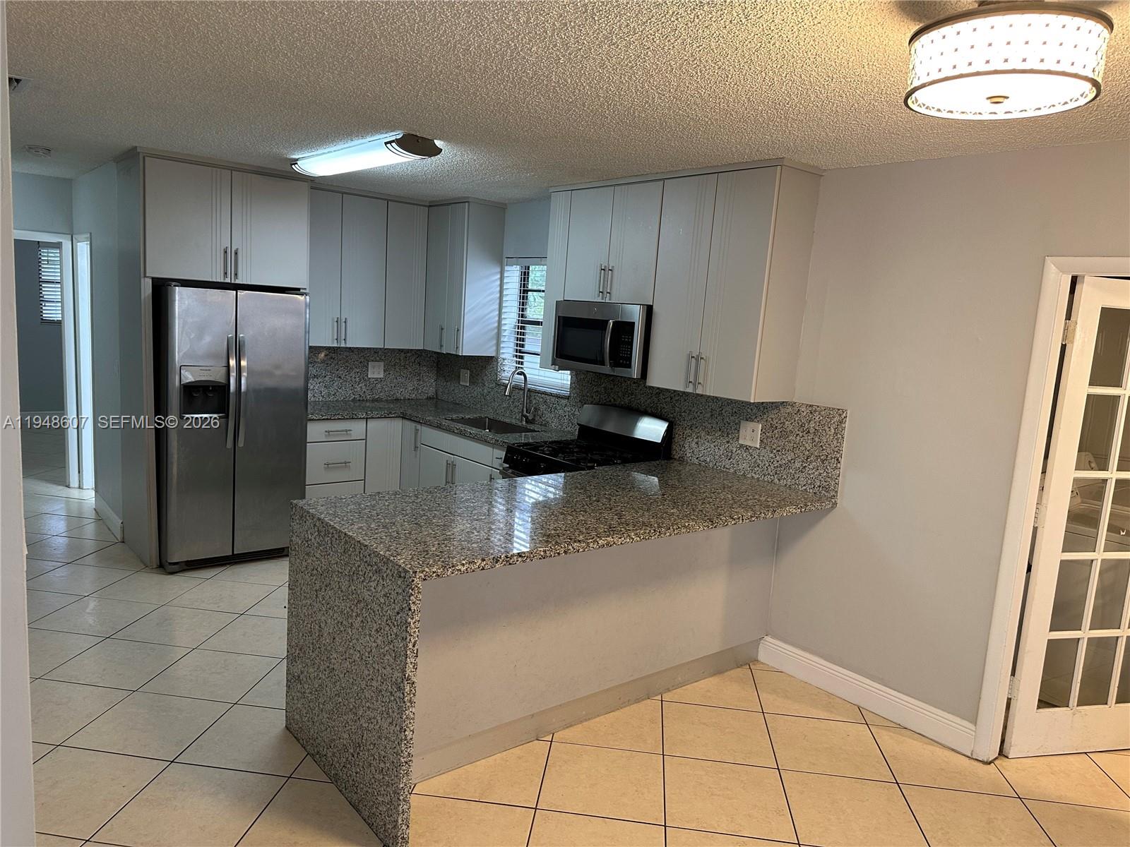 7860 Southwest 16th Street Miami, FL 33155 - Photo 21 of 32 a kitchen with stainless steel appliances granite countertop a refrigerator a stove a sink a washer and dryer