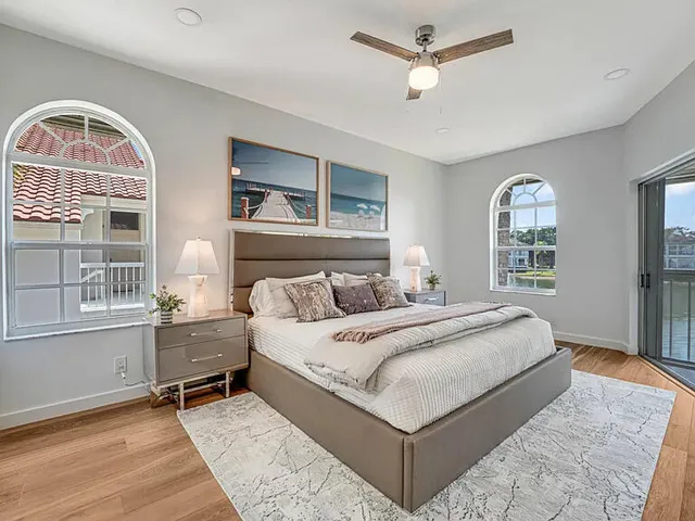a bedroom with a bed television on desk and a window