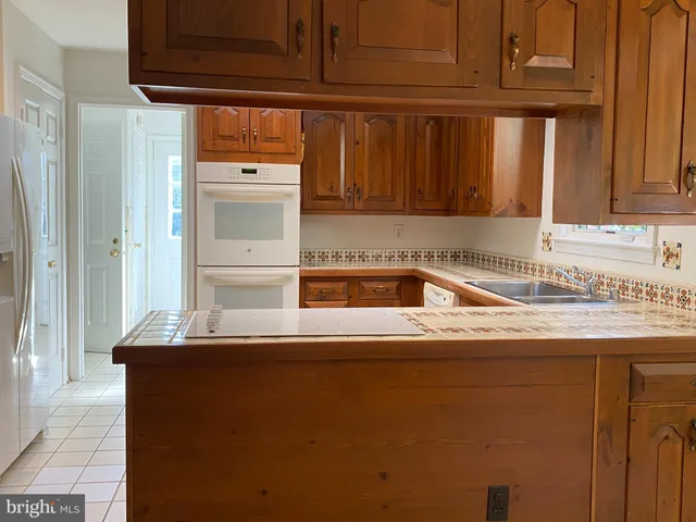 a kitchen with stainless steel appliances granite countertop a refrigerator a stove and a sink with wooden cabinets