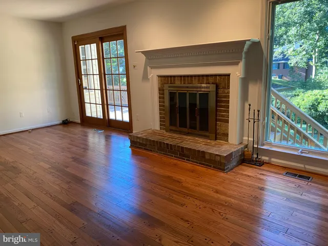 an empty room with wooden floor fireplace and windows