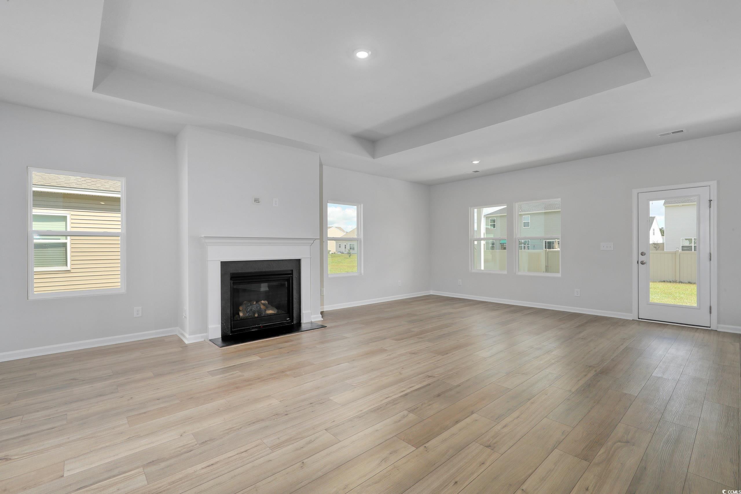 Unfurnished living room with a tray ceiling and li