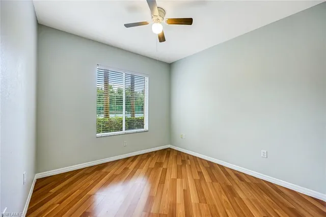 a view of empty room with wooden floor and fan