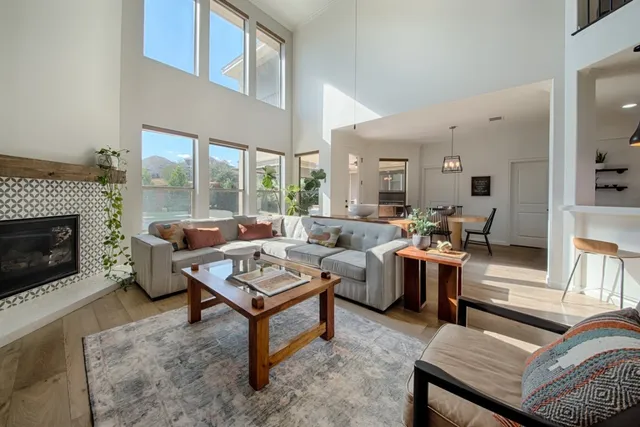a living room with furniture dining table a fireplace and a large window