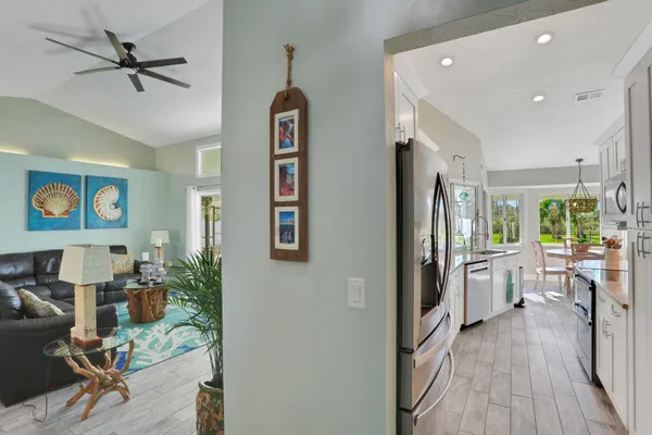 a dining room with wooden floor a chandelier a glass table and chairs