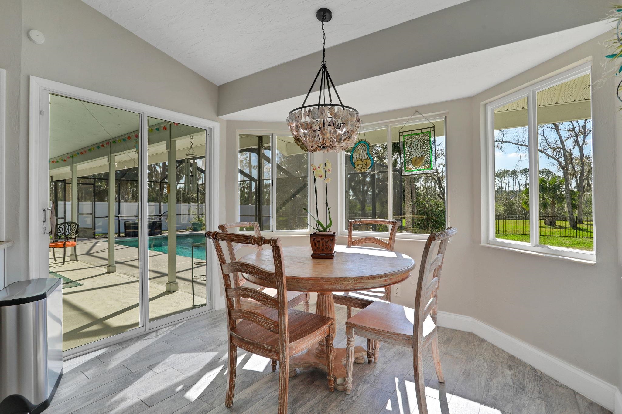 1075 Lambert Avenue Flagler Beach, FL 32136 - Photo 21 of 71 a dining room with wooden floor a chandelier a glass table and chairs