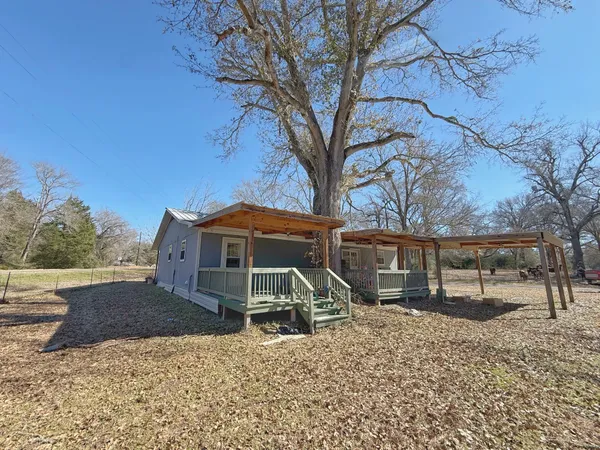 a front view of a house with a yard and large trees