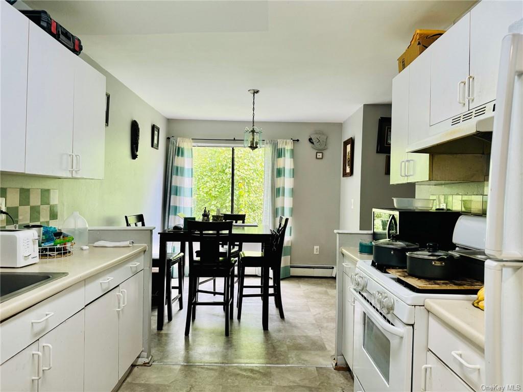 3(33J) Hook Road, Unit 14E Poughkeepsie, NY 12601 - Photo 5 of 12 a kitchen with stainless steel appliances a stove a sink a microwave a dining table and chairs with wooden floor