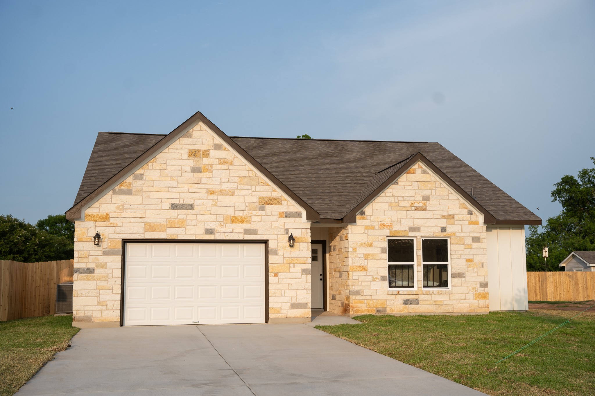 304 String Prairie Way Smithville, TX 78957 - Photo 2 of 30 French country style house featuring roof with shingles, concrete driveway, an attached garage, and stone siding