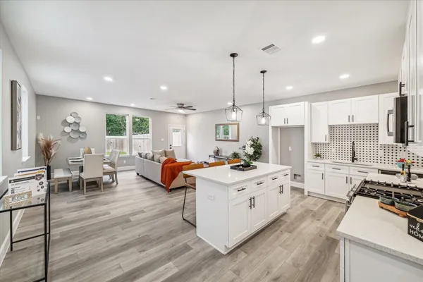 a kitchen with stainless steel appliances kitchen island a stove a refrigerator a oven and a dining table with wooden floor