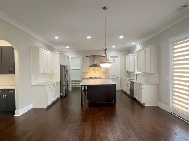 a large white kitchen with a window and stainless steel appliances