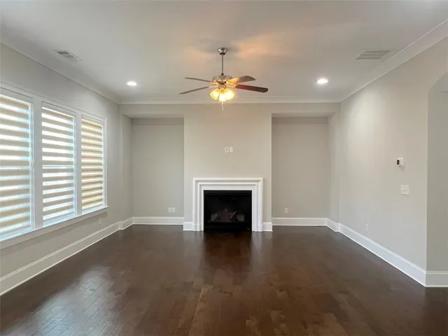 an empty room with windows fireplace and wooden floor
