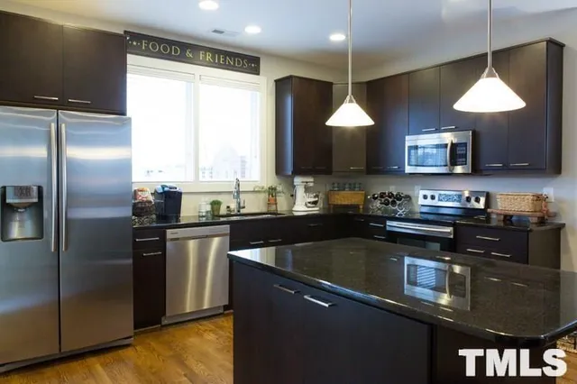 a kitchen with stainless steel appliances granite countertop a sink a stove and a refrigerator