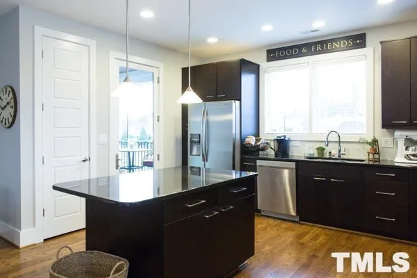 a large kitchen with kitchen island granite countertop a refrigerator a sink and wooden cabinets