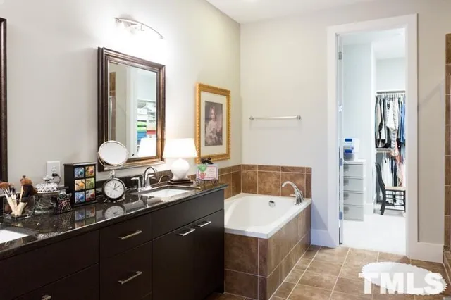 a bathroom with a tub double sink window and mirror