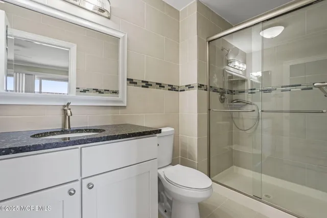 a bathroom with a granite countertop sink a toilet and a shower