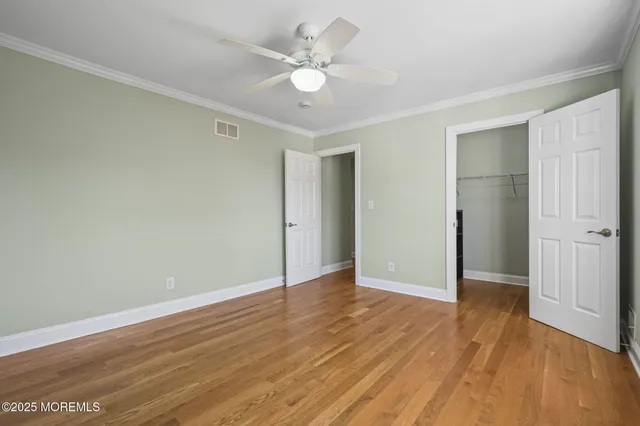an empty room with wooden floor and a ceiling fan