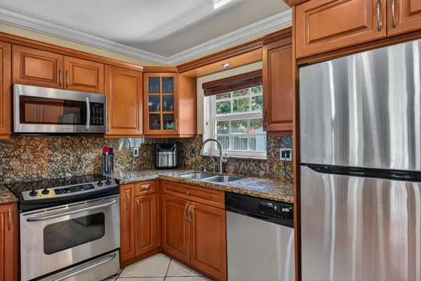 a kitchen with granite countertop a refrigerator stove top oven and sink