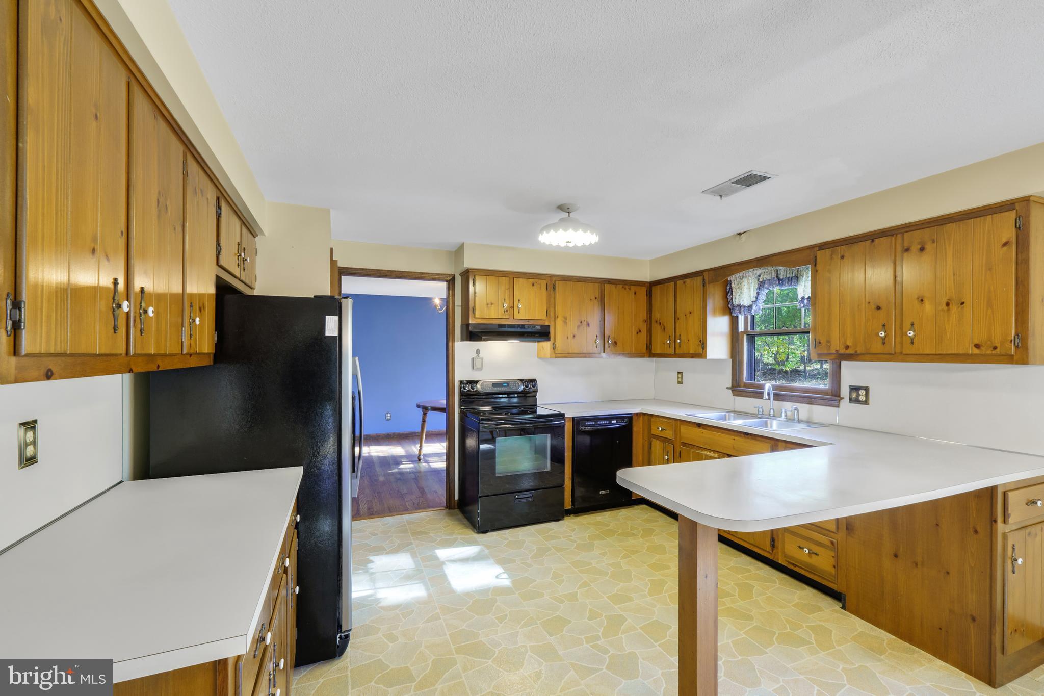 2333 Three Mile Run Road Perkasie, PA 18944 - Photo 9 of 43 a kitchen with stainless steel appliances kitchen island granite countertop a refrigerator a stove and a sink with wooden floor