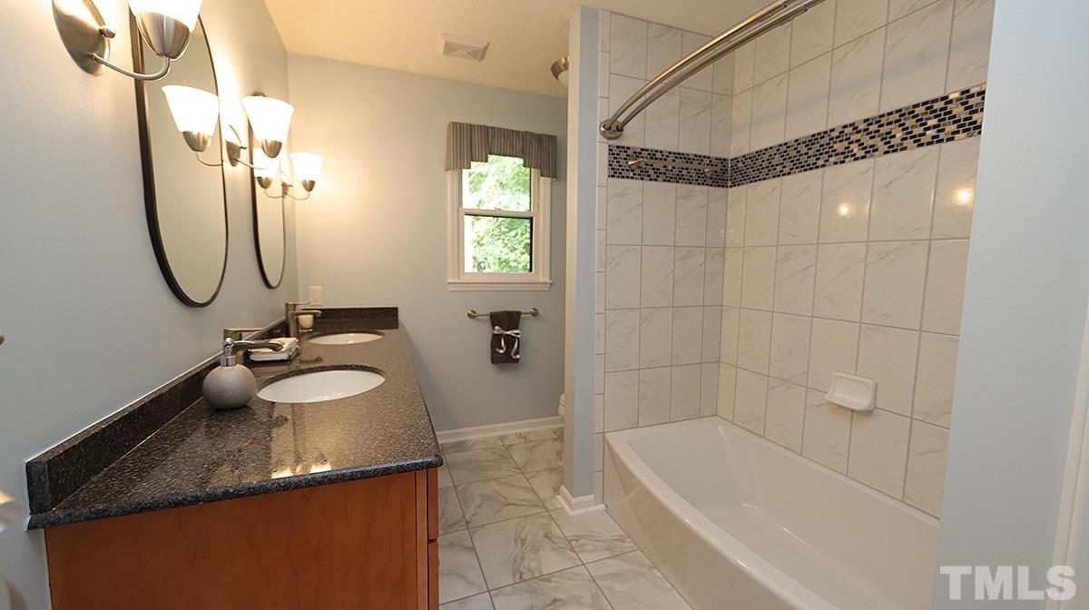 9627 Barton Creek Road Raleigh, NC 27615 - Photo 21 of 30 a bathroom with a granite countertop sink a mirror and a bathtub