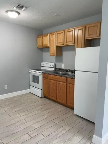 a kitchen with stainless steel appliances granite countertop a refrigerator a sink dishwasher a stove with wooden cabinets