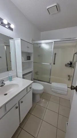 a bathroom with a granite countertop sink toilet a mirror and shower