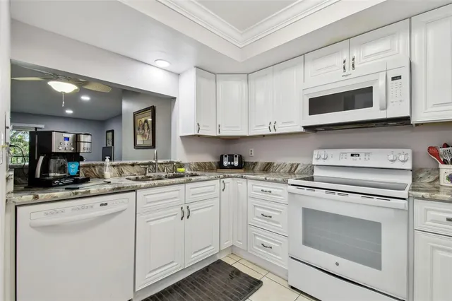 a kitchen with granite countertop white cabinets and white appliances