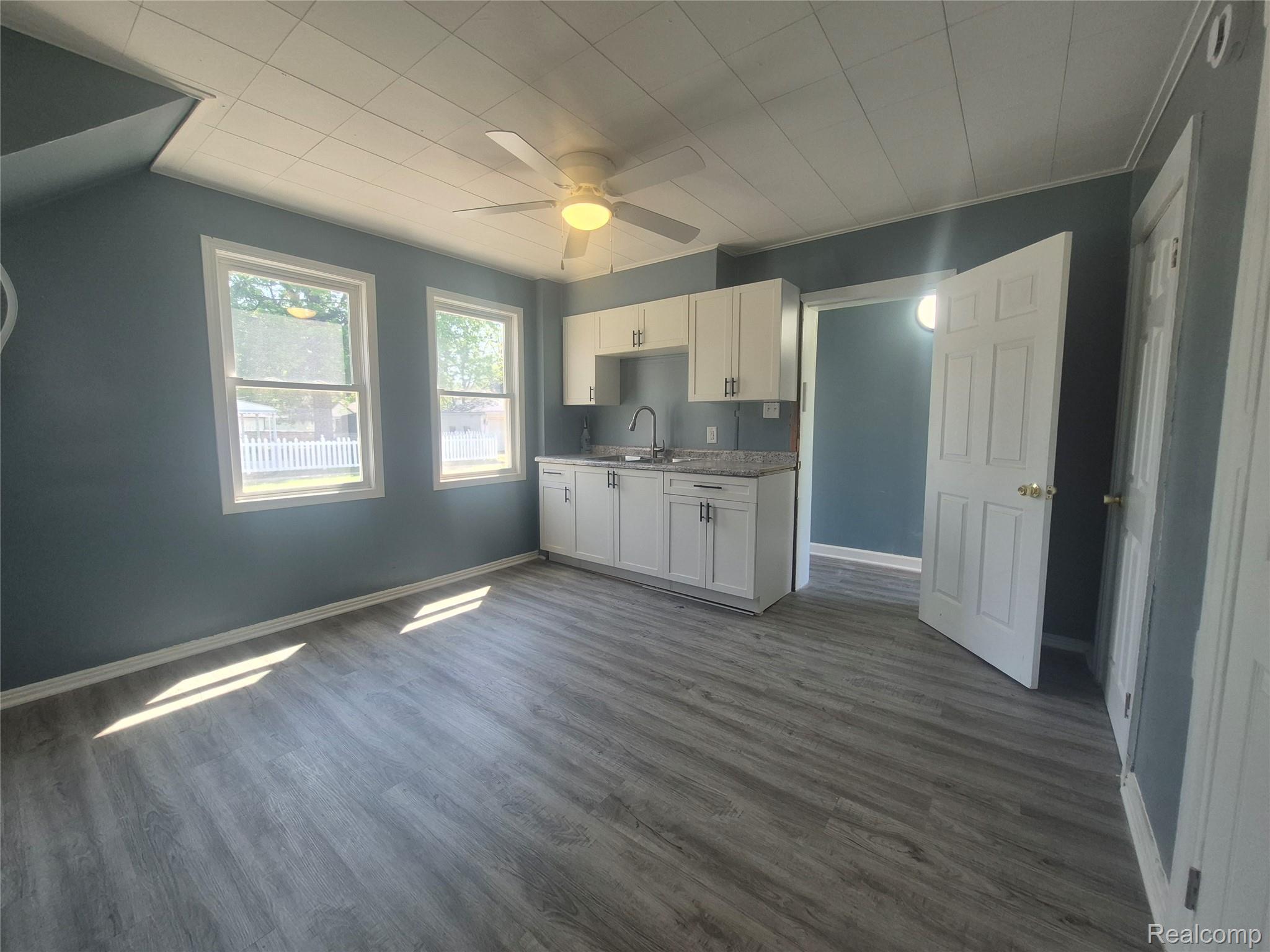 16758 Frazho Road Roseville, MI 48066 - Photo 9 of 53 Compact kitchen area featuring white cabinetry, a single basin sink, and wood-finish flooring