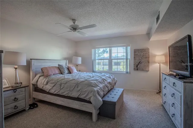 a spacious bedroom with a bed and a flat screen tv