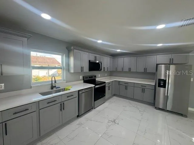 a large kitchen with stainless steel appliances lots of white cabinets
