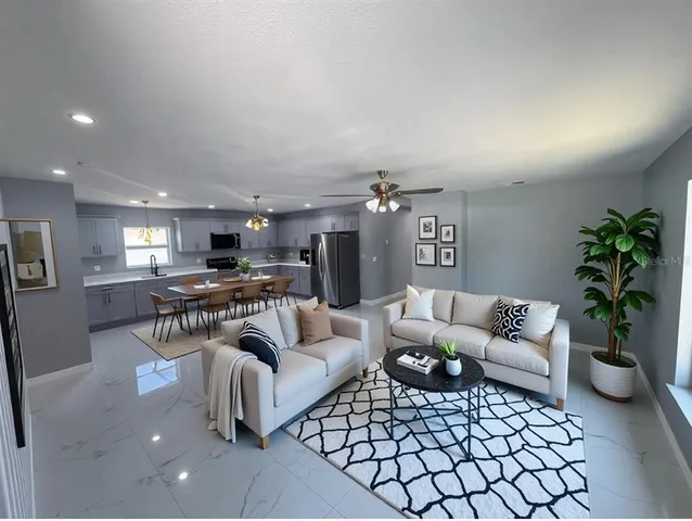 a kitchen with stainless steel appliances a sink a stove a refrigerator cabinets a dining table and chairs