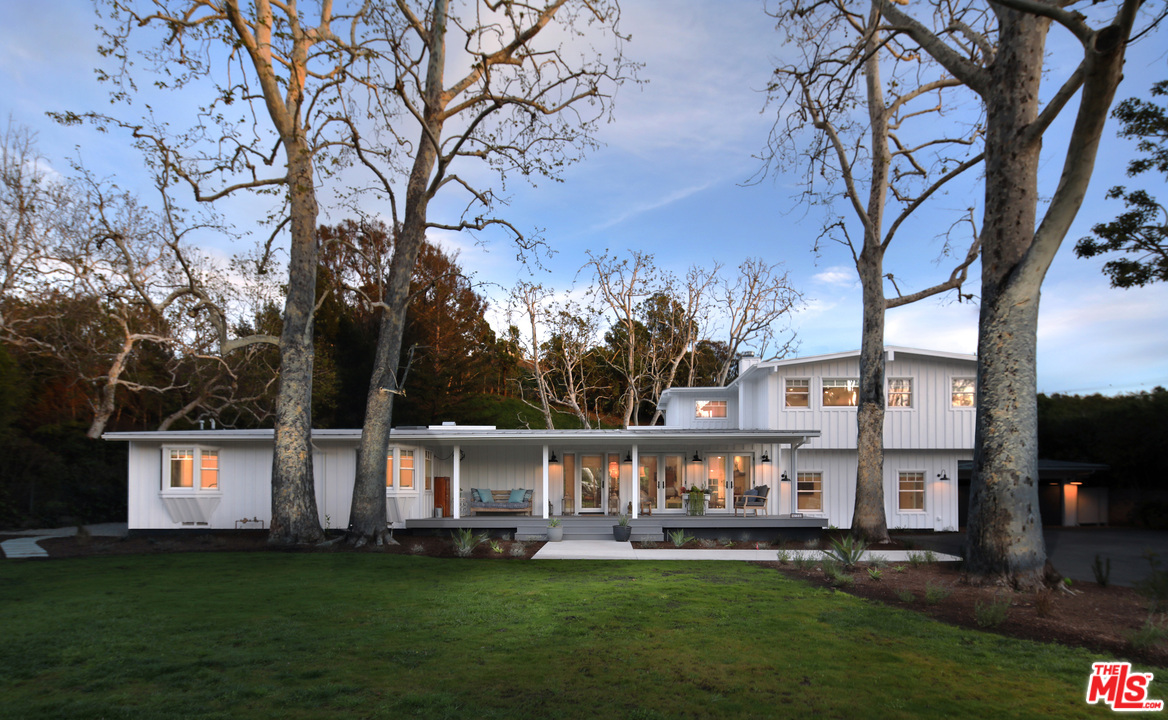 a front view of a house with a garden and trees