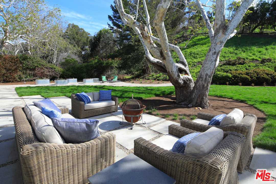 6152 Bonsall Drive Malibu, CA 90265 - Photo 8 of 26 a view of patio with couches table and chairs under an umbrella with large trees
