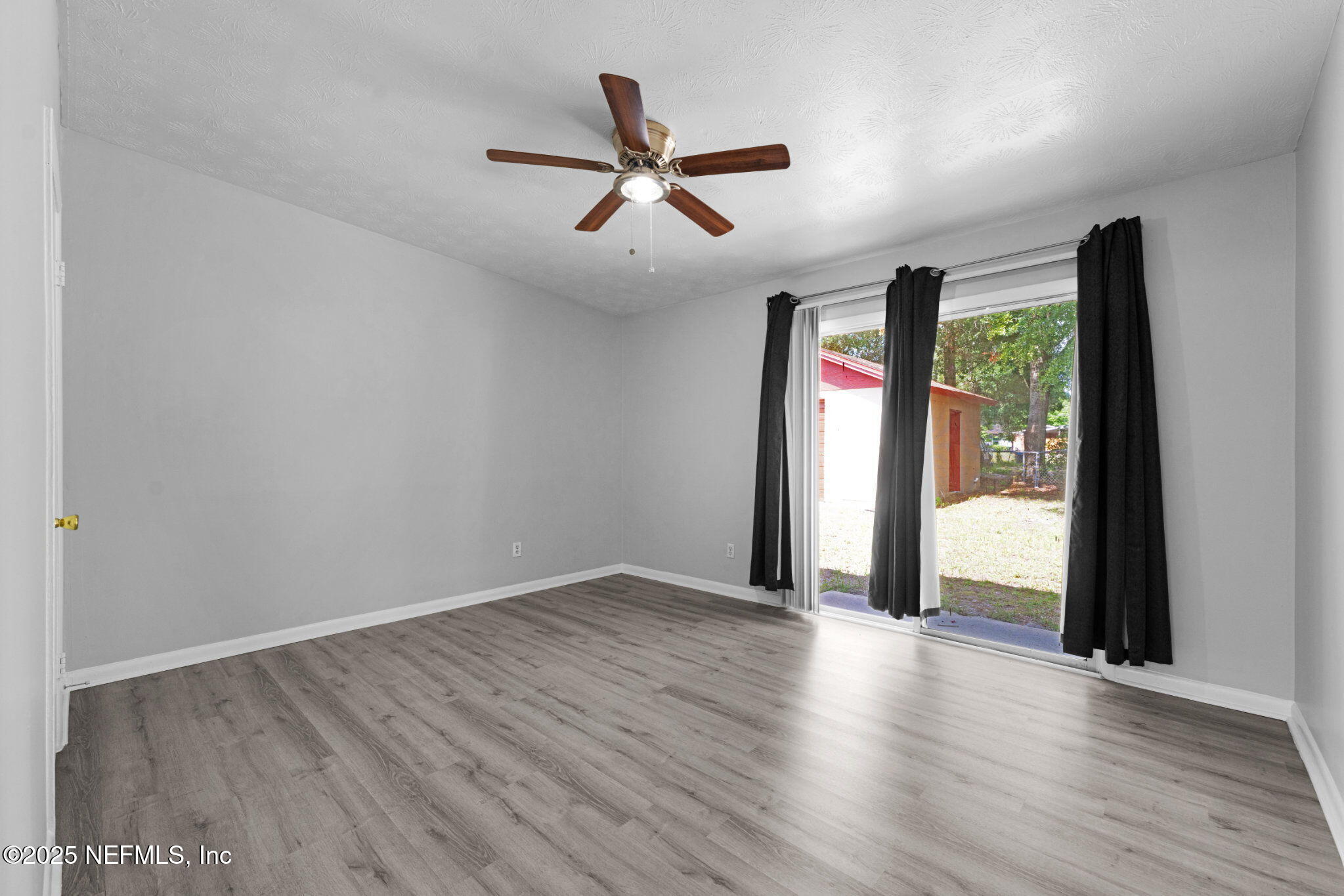 2254 Firestone Road Jacksonville, FL 32210 - Photo 8 of 20 an empty room with wooden floor a ceiling fan and windows