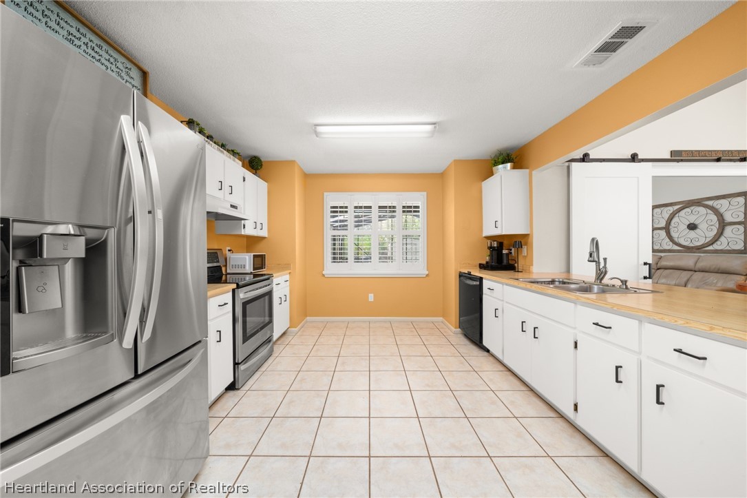 3103 Duffer Road Sebring, FL 33872 - Photo 3 of 29 a large white kitchen with granite countertop a refrigerator a sink a stove a washer and dryer
