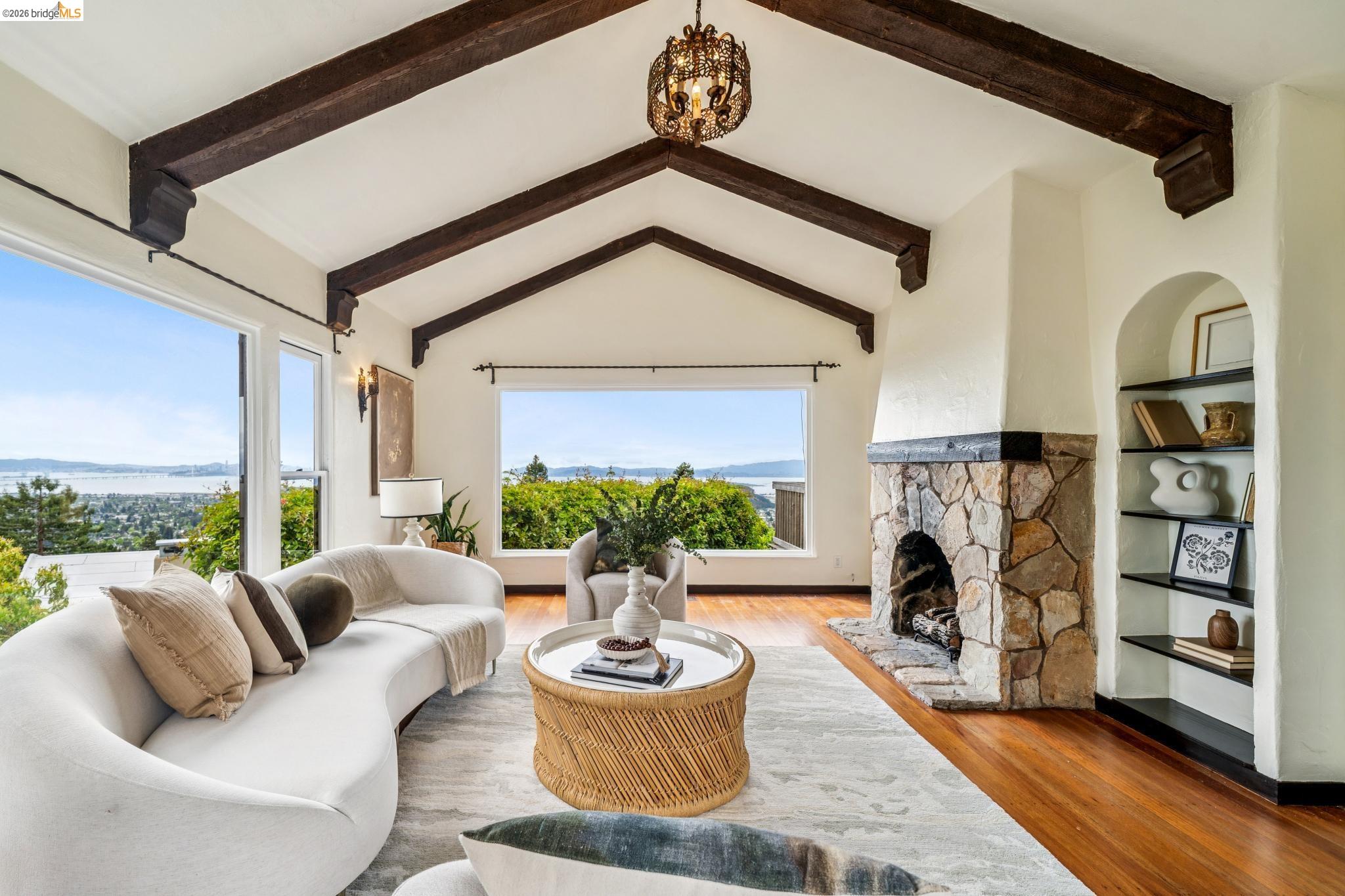 784 Cragmont Avenue Berkeley, CA 94708 - Photo 16 of 64 Living area featuring vaulted ceilings with exposed wood beams, a stone-clad fireplace, and hardwood flooring